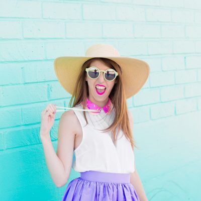 A woman wearing a hat standing in front of a blue wall