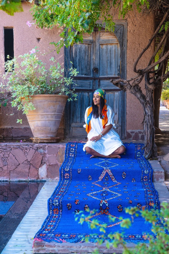 Large blue moroccan rug with woman sitting on it on stairs