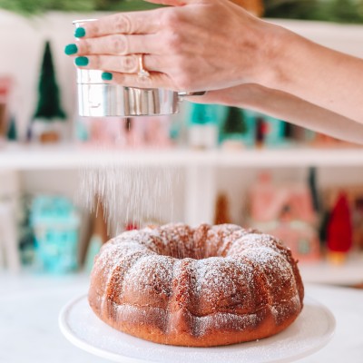 Coffee bundt cake being dusted with powdered sugar