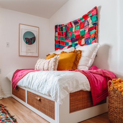 Rattan IKEA daybed with pillows on top and a rug hanging behind it