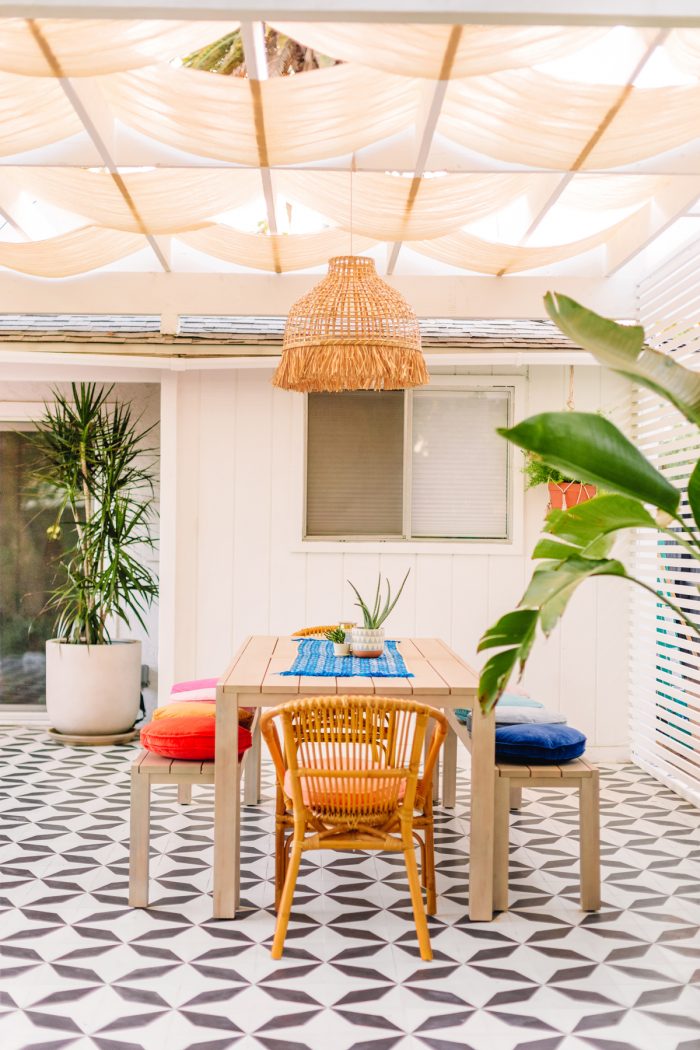 Black and white tile patio with dining table and colorful pillows with a pergola above it