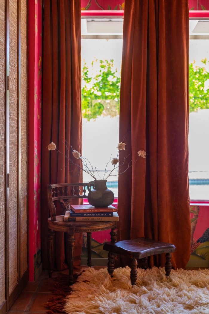 velvet curtains with wood chair in front stacked with books