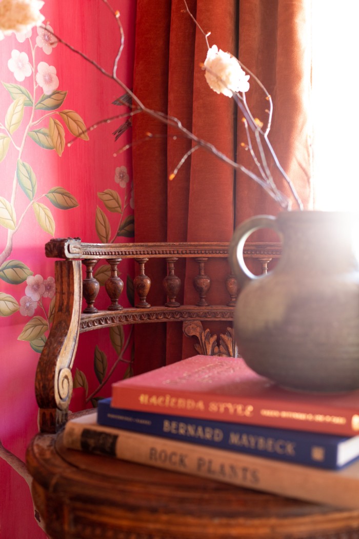 Wood chair with books stacked on top and vase with branches