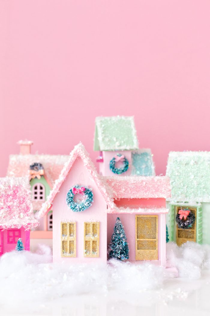 Small Christmas village with a pink background. 
