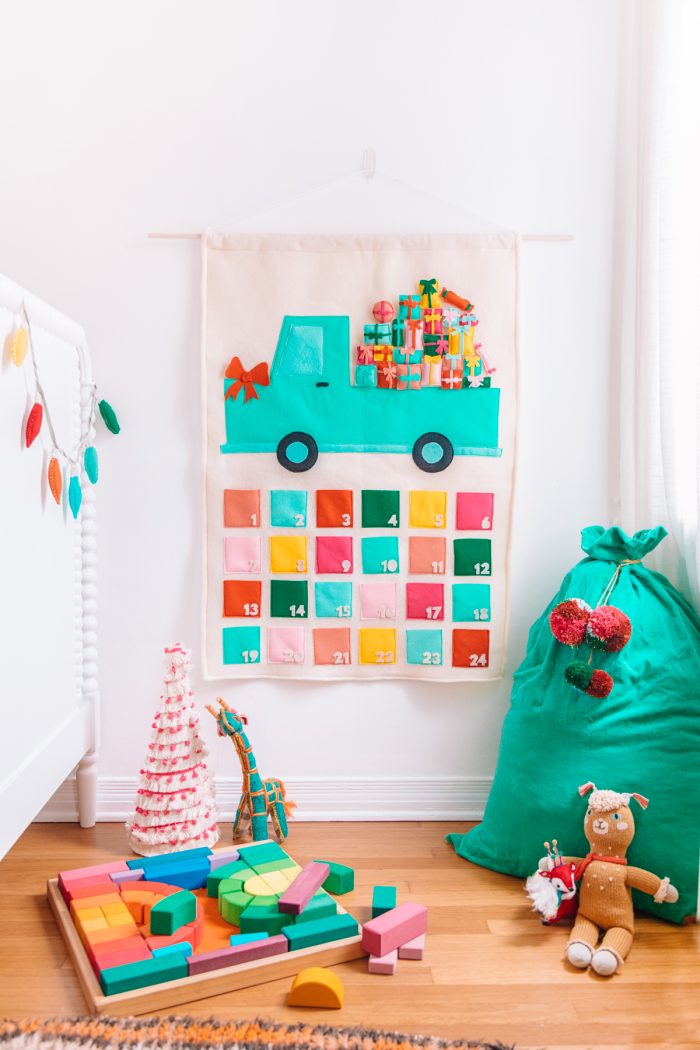 Felt advent calendar with a truck design on it hanging on a wall. 