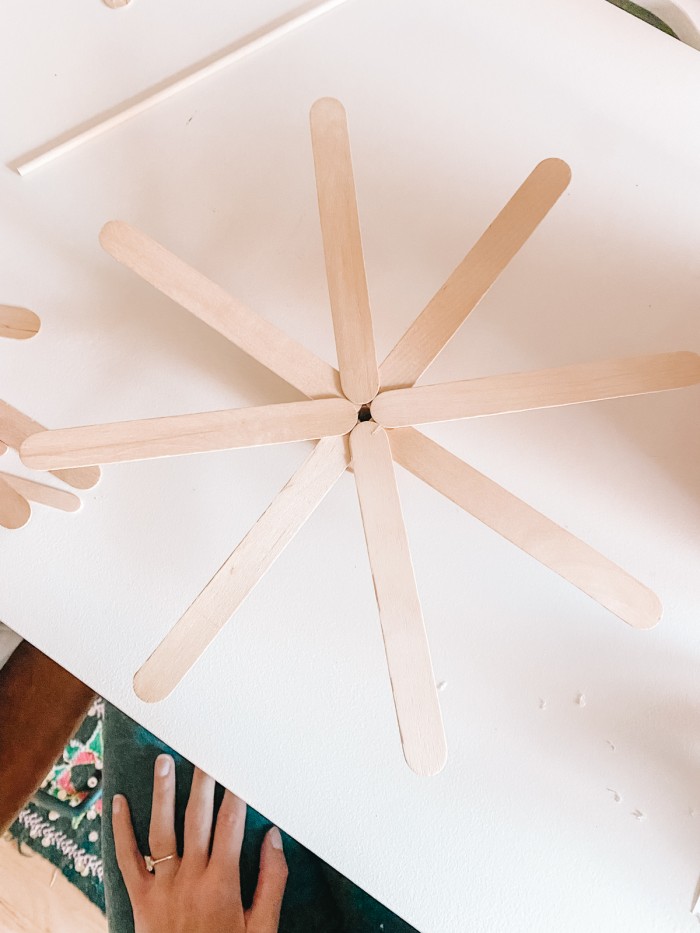 Eight popsicle sticks in a starburst shape on a white table