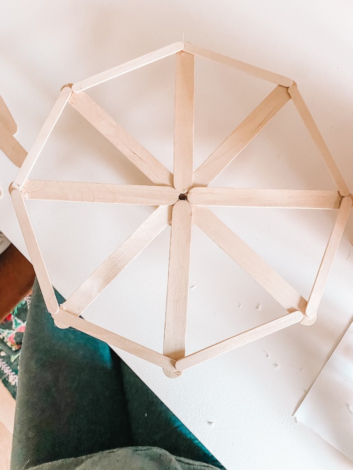 Popsicle sticks in a Ferris wheel shape laying on a white table