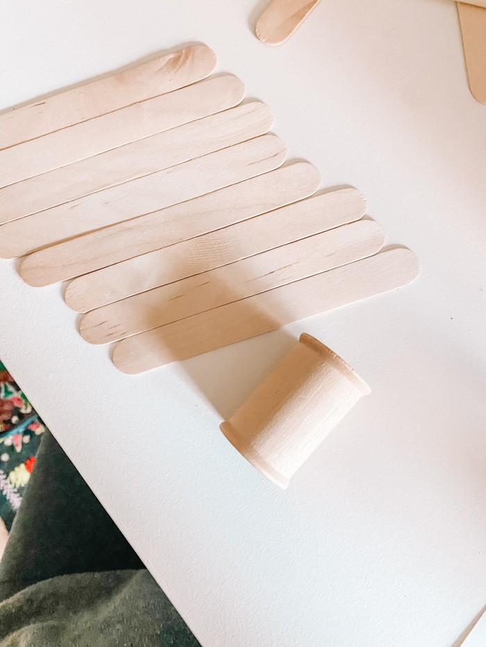 Popsicle sticks and a wooden spool laying on a table