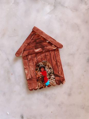 A wooden house ornament with a picture of a boy in the middle