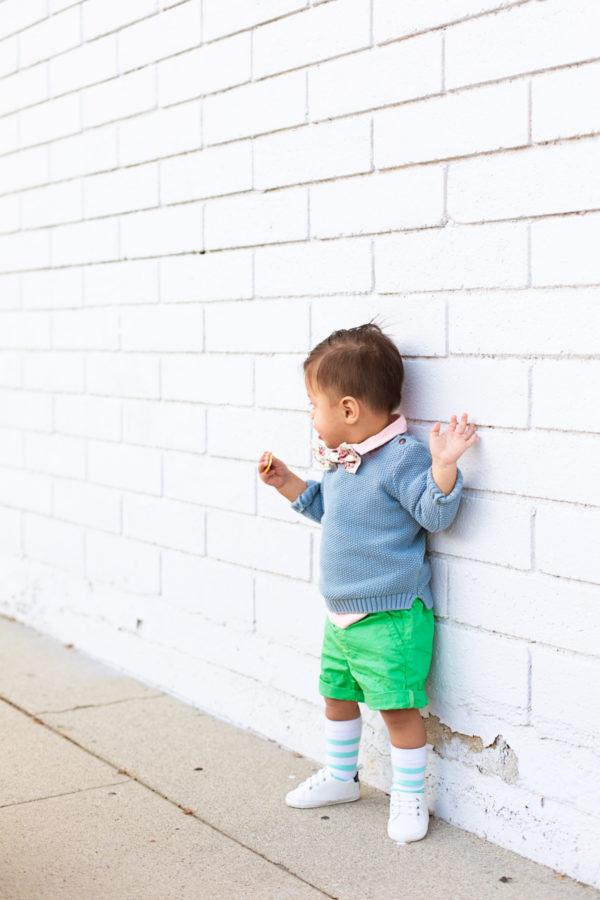 A little boy standing in front of a white brick