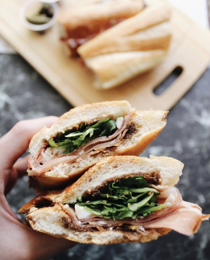 Larchmont Wine and Cheese Proscuitto Sandwich held about a table