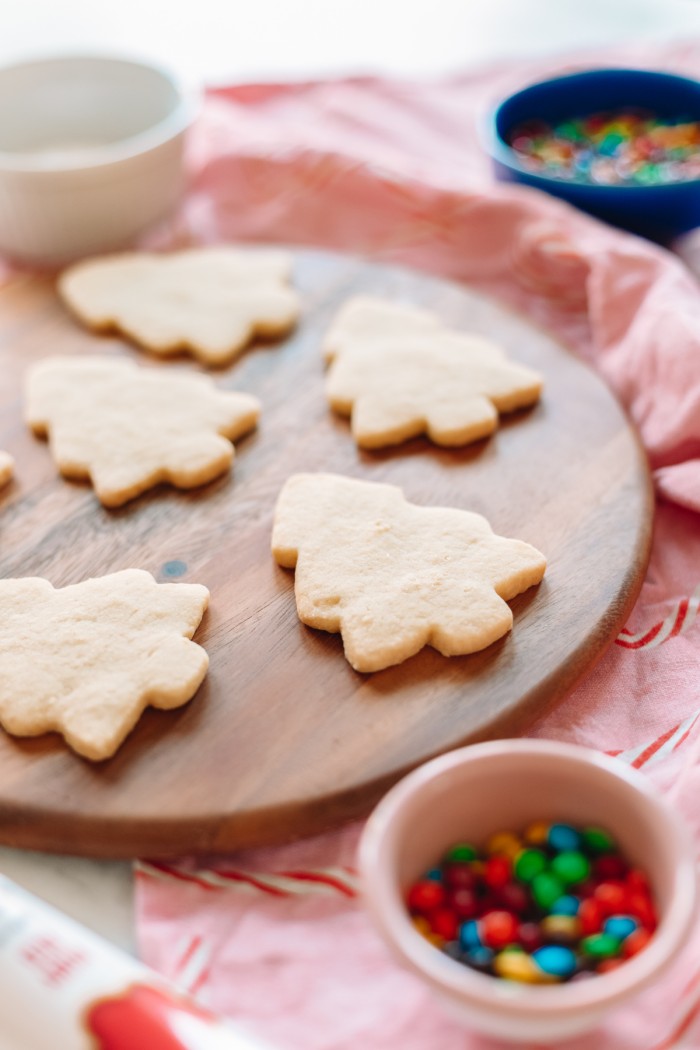 Cookies on a wood cutting board with m&ms in a bowl in front