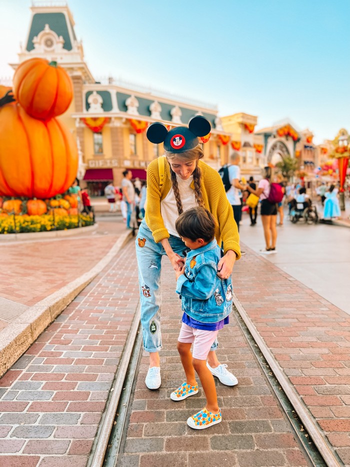 Mom and son on Main Street at Disneyland with Mickey Pumpkin behind them
