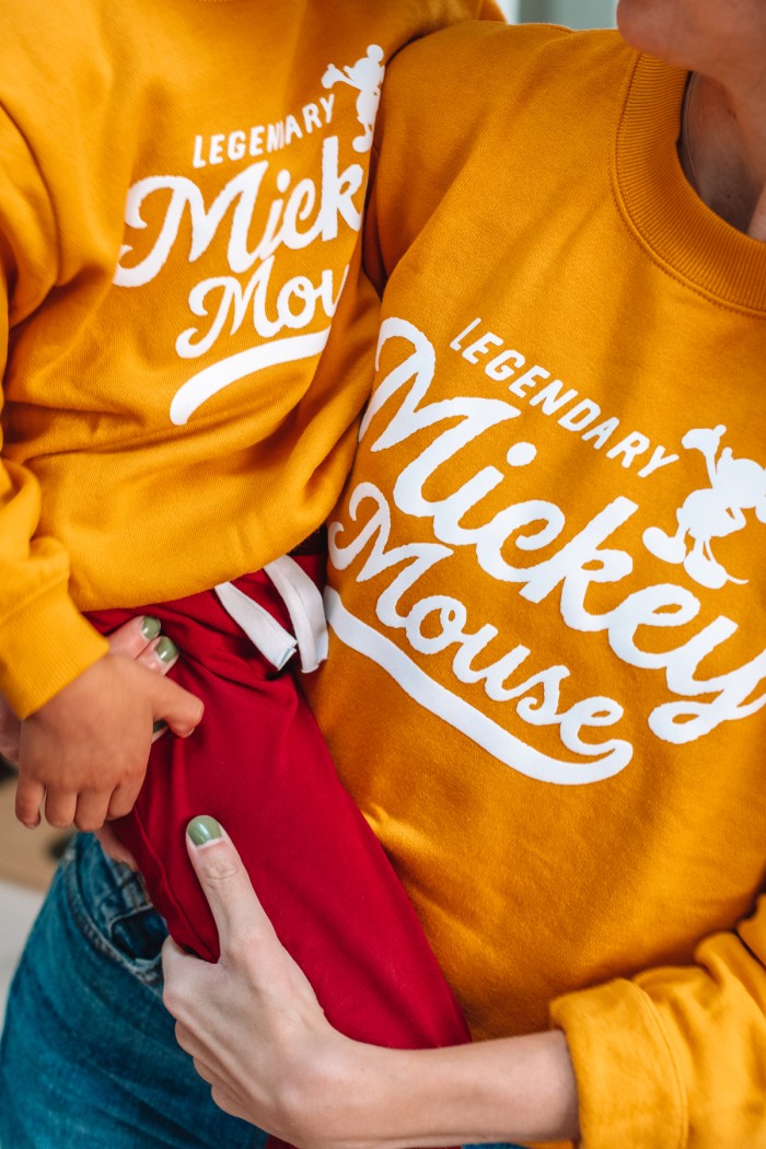 Mom holding child in matching Disney sweatshirts