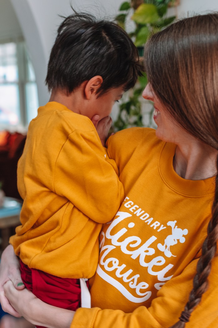 Mom holding child in matching yellow sweatshirts