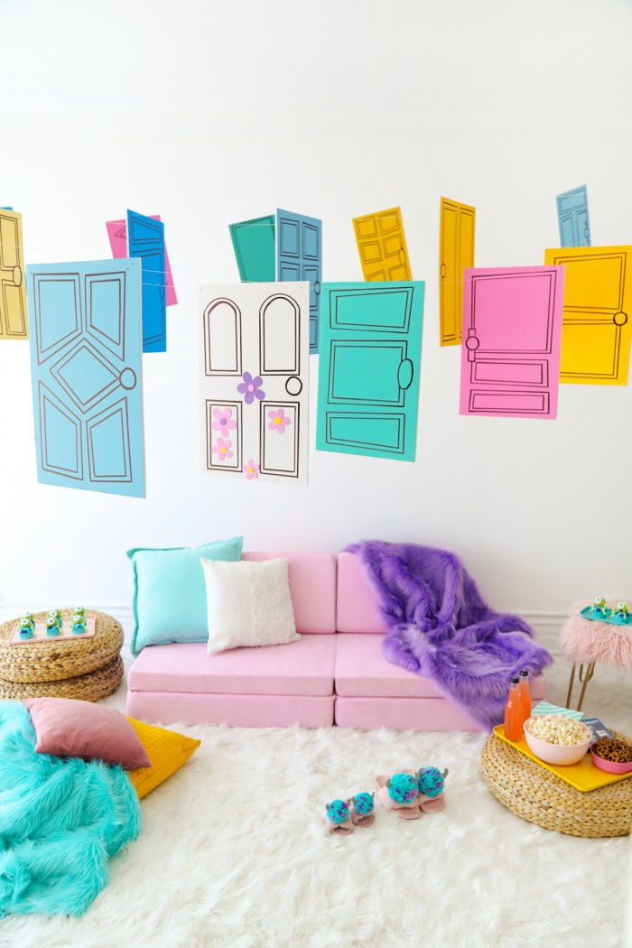 Pink couch with colorful Monster's Inc door decorations hanging above it on a white faux fur rug