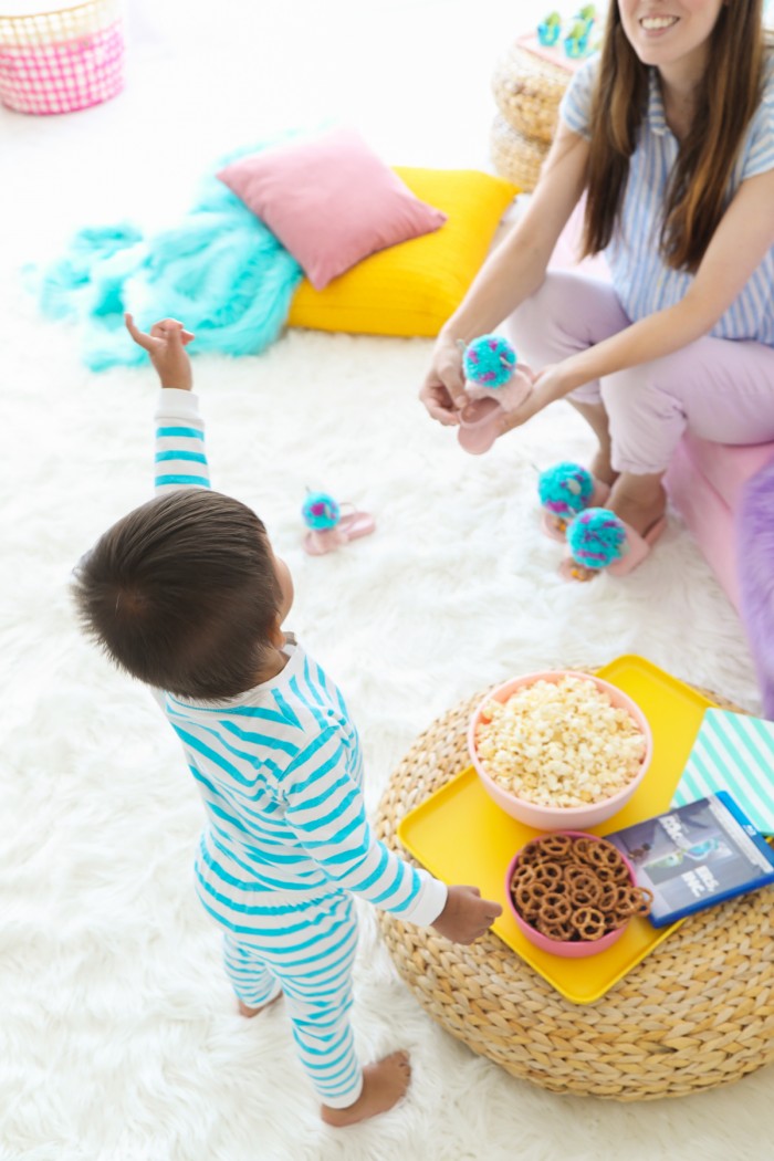 Child with snacks on an ottoman and white faux fur rug