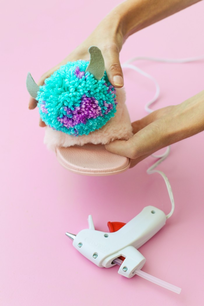 Blue and purple monster Pom Pom being hot glued to a pink slipper