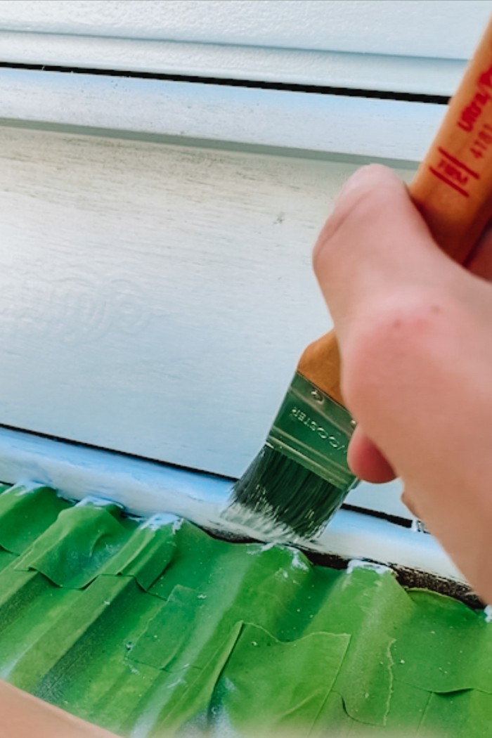 Paint brush touch ups on painted piano with piano keys covered in painter's tape