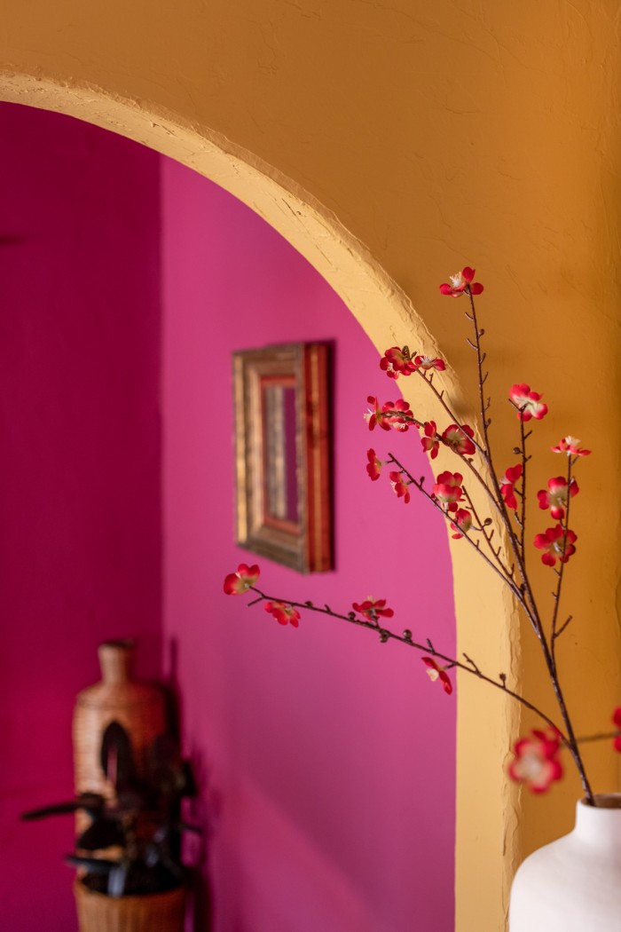 yellow arch with pink room behind it and red flowers