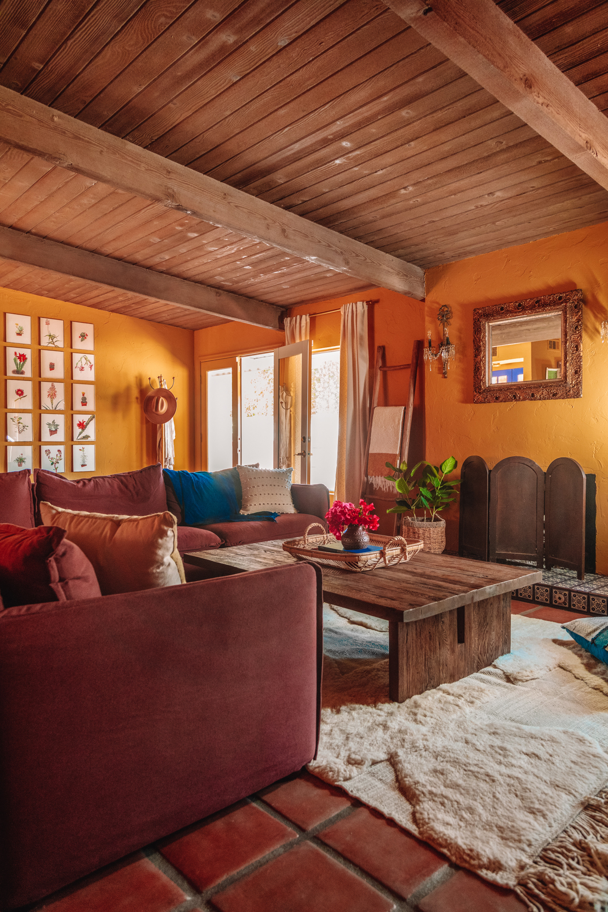 Plum couch with white rug in an ochre living room