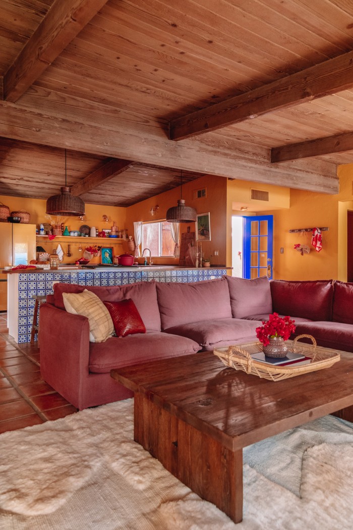 Purple couch in yellow room with kitchen behind it