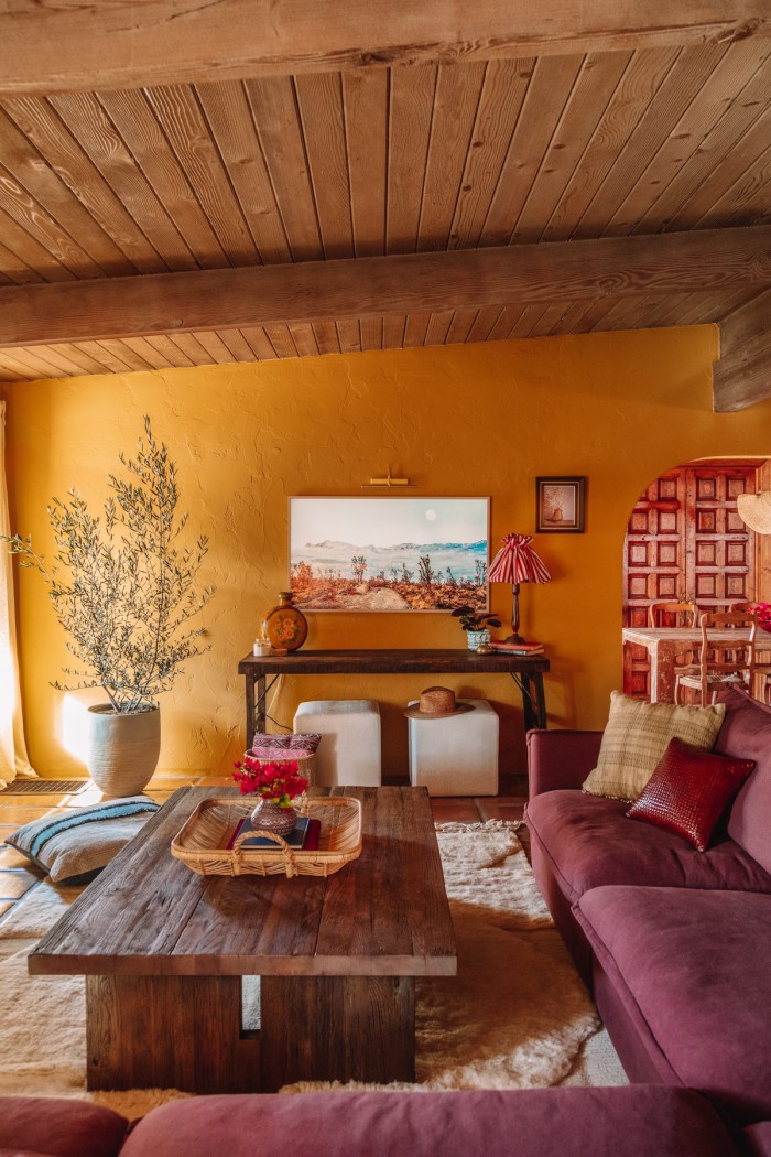 frame TV over antique table with couch in ochre living room