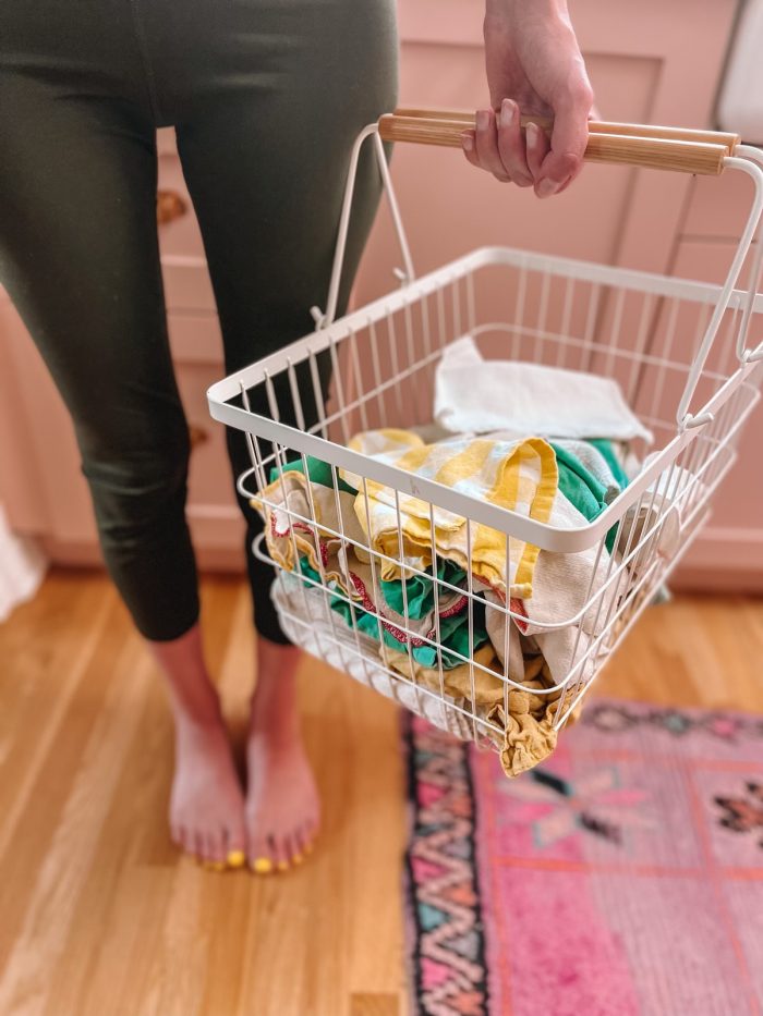 woman holding white metal basket with dirty unpaper towels