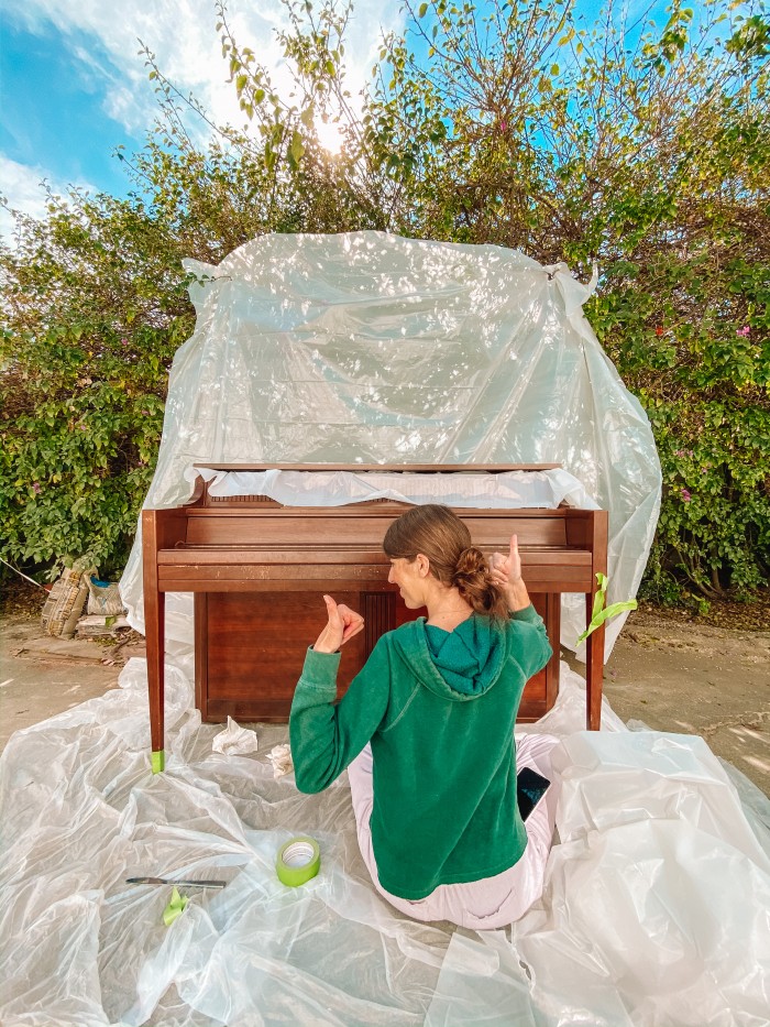 Wood piano in front of plastic tarp