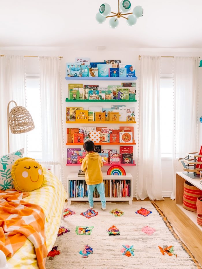 A rainbow-colored shelf with a boy standing in front of it