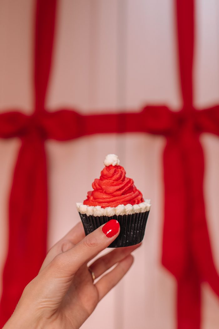 A person holding a Santa hat cupcake