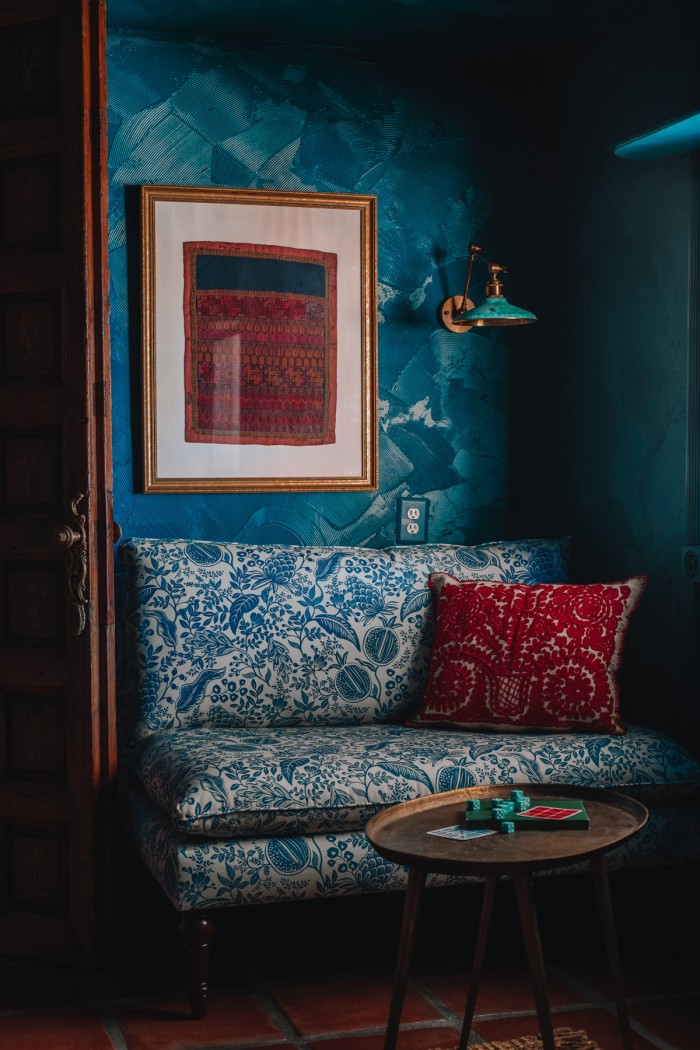 blue floral chair with red pillow in teal room