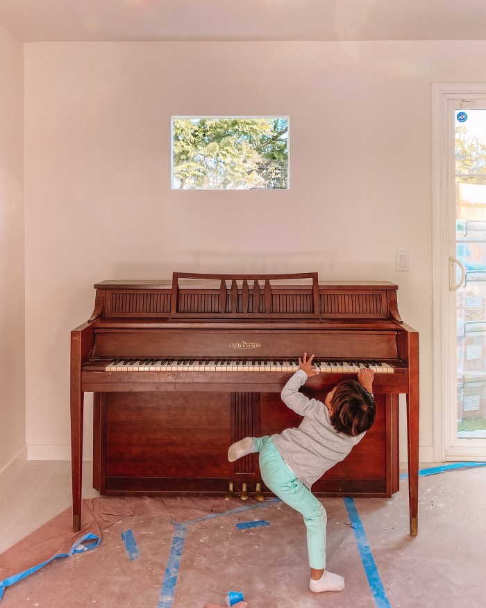 Wood piano with child playing in front of it