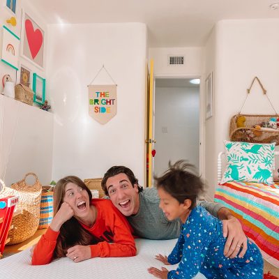 A group of people sitting on a bed laughing