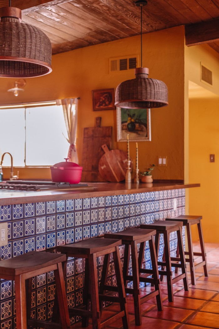 yellow kitchen with blue and white tiled peninsula and butcher block counters 