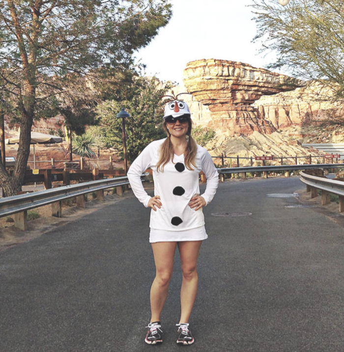 Woman standing in a road, dressed as Olaf the snowman. 