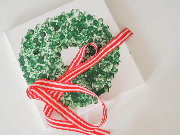 Fingerprint wreath on a canvas with a red ribbon on top. 